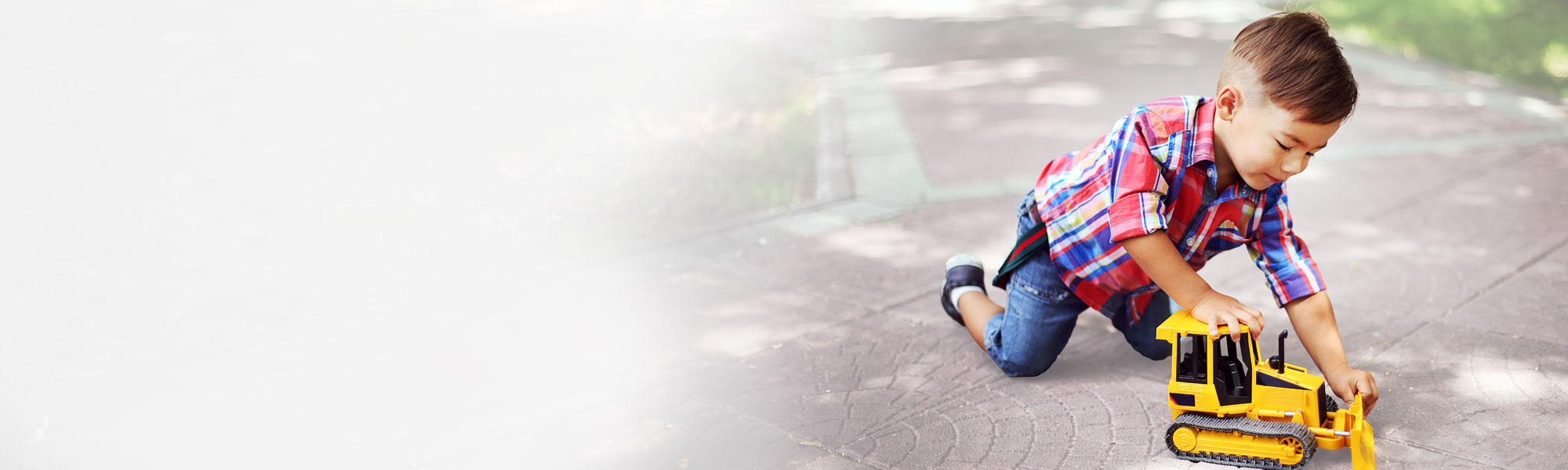 Curious young boy playing with toy bulldozer in the backyard