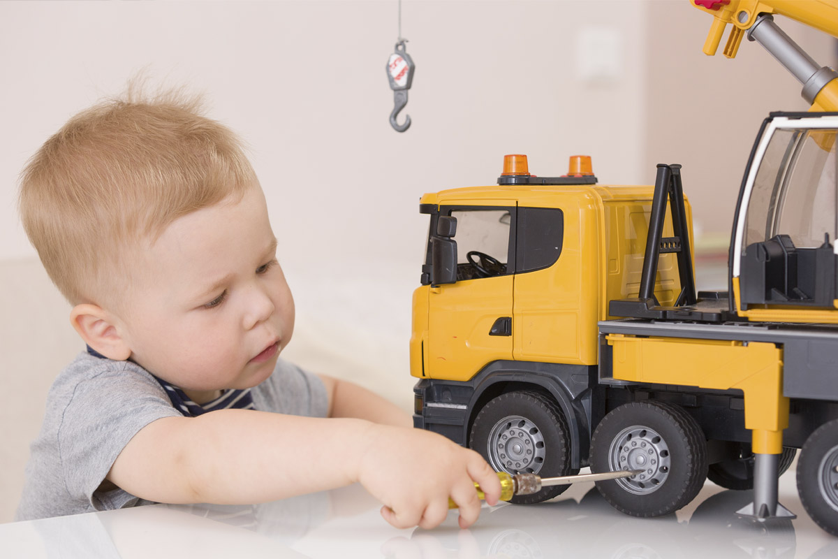 Toddler boy playing with toy truck crane while learning and exploring